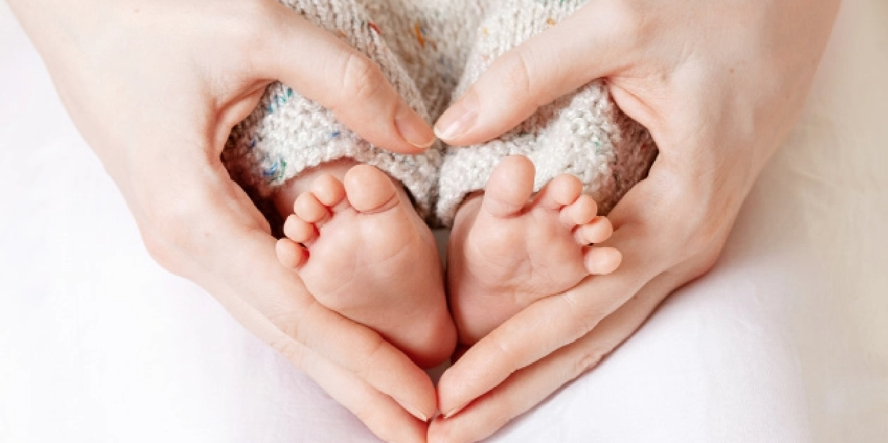 Hands making heart around baby feet