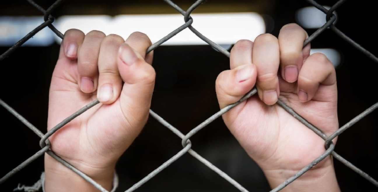 Hands holding chainlink fence