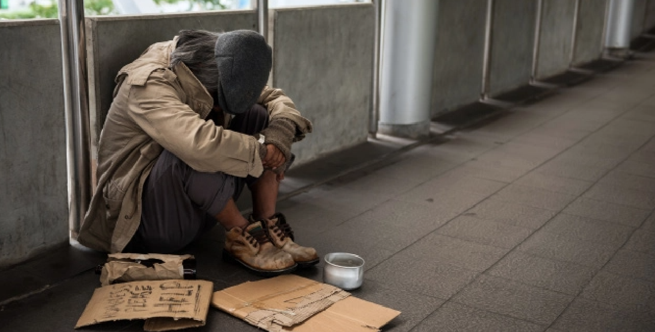 Homelss man sitting on ground with cardboard signs